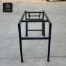 The black metal frame of a folding banquet table, showing its sturdy construction outdoors.