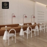 A cafe with channel-tufted seating, round tables, and modern arch-back chairs.