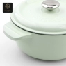 A close-up view of the handle and side of a light green enamel cast iron Dutch oven.