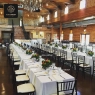 Black wooden Chiavari chairs at long tables in a rustic banquet hall.