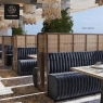 A row of elegant navy blue upholstered booths with rattan dividers and patterned floor tiles.