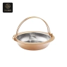 A gold-colored hot pot with a hammered, divided silver interior and a large handle.