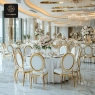 A spacious event hall with multiple tables and chairs, adorned with floral centerpieces.