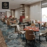 A restaurant with square decorative pattern tables and light-colored chairs.