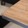A close-up of a Series E wood table top with a rounded metal edge.
