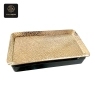 A gold rectangular plastic tray with a hammered texture rests on a black base.