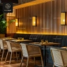Rattan chairs and a long dark booth in a restaurant with wooden walls.