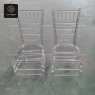 Two clear resin Chiavari chairs without pads, front view, in a warehouse.