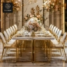 Long white marble table with gold-framed chairs in a luxurious setting.