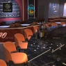 Bar stools around a black marble bar in a nightclub.