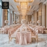 A luxurious banquet hall with long tables and chairs draped in pink fabric.