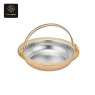 A gold-colored hot pot with a hammered silver interior and a large handle.