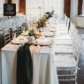 Clear resin Chiavari chairs with white pads at a long banquet table.