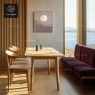 A dining space with a wooden table and chairs, and a long purple banquet seat by the window.