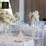 Clear resin Chiavari chairs with white pads at a formal event with floral centerpieces.