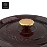 Close-up of the gold knob and 'Success' embossed on the dark red dutch oven lid.