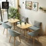 A modern dining setup with square tables, light blue chairs, and lush green plants.
