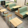 Dining area with multiple green booths, square tables, and wooden chairs.