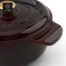 A close-up of the handle and lid of a dark red dutch oven with a gold knob.