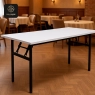 A white rectangular folding banquet table with a black metal frame, set outdoors on concrete.