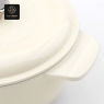 A close-up view of the handle and lid of a cream-colored enamel cast iron dutch oven.