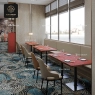 A restaurant row with decorative pattern tables and light seating next to windows.
