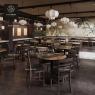 Stone table tops with dark chairs in a restaurant with tropical wallpaper.