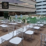 Clear resin Chiavari chairs with white pads set up for an outdoor event.