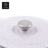 A close-up view of the handle and the speckled lid of a white heart-shaped enamel pot.