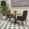 Two beige high-back dining armchairs at a small square table in a cafe.