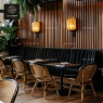 Rattan chairs and a long black booth in a dining area with warm lighting.