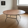 Round wood grain event table with black foldable legs in an indoor setting.