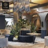 A modern restaurant space featuring plush seating, large potted plants, and exposed ceiling elements.