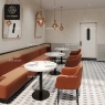 A restaurant featuring white stone tables, orange seating, and a patterned floor.