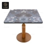A decorative pattern table with a wood-like column and a copper-colored base.