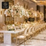 A luxurious dining hall with a long marble table and elegant gold-framed chairs.
