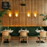 Rattan chairs with green seats and a long green booth in a restaurant.