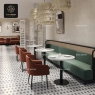 A restaurant with white stone tables and brown chairs along a green booth.
