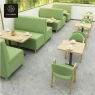 A restaurant setting with light-green upholstered booths, tables, and matching chairs.
