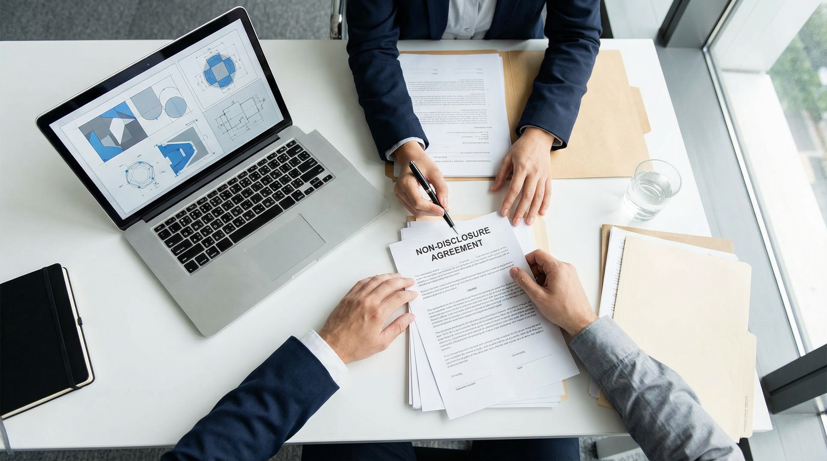 Buyer and supplier signing an NDA agreement with design files visible on laptop before sharing custom product specifications