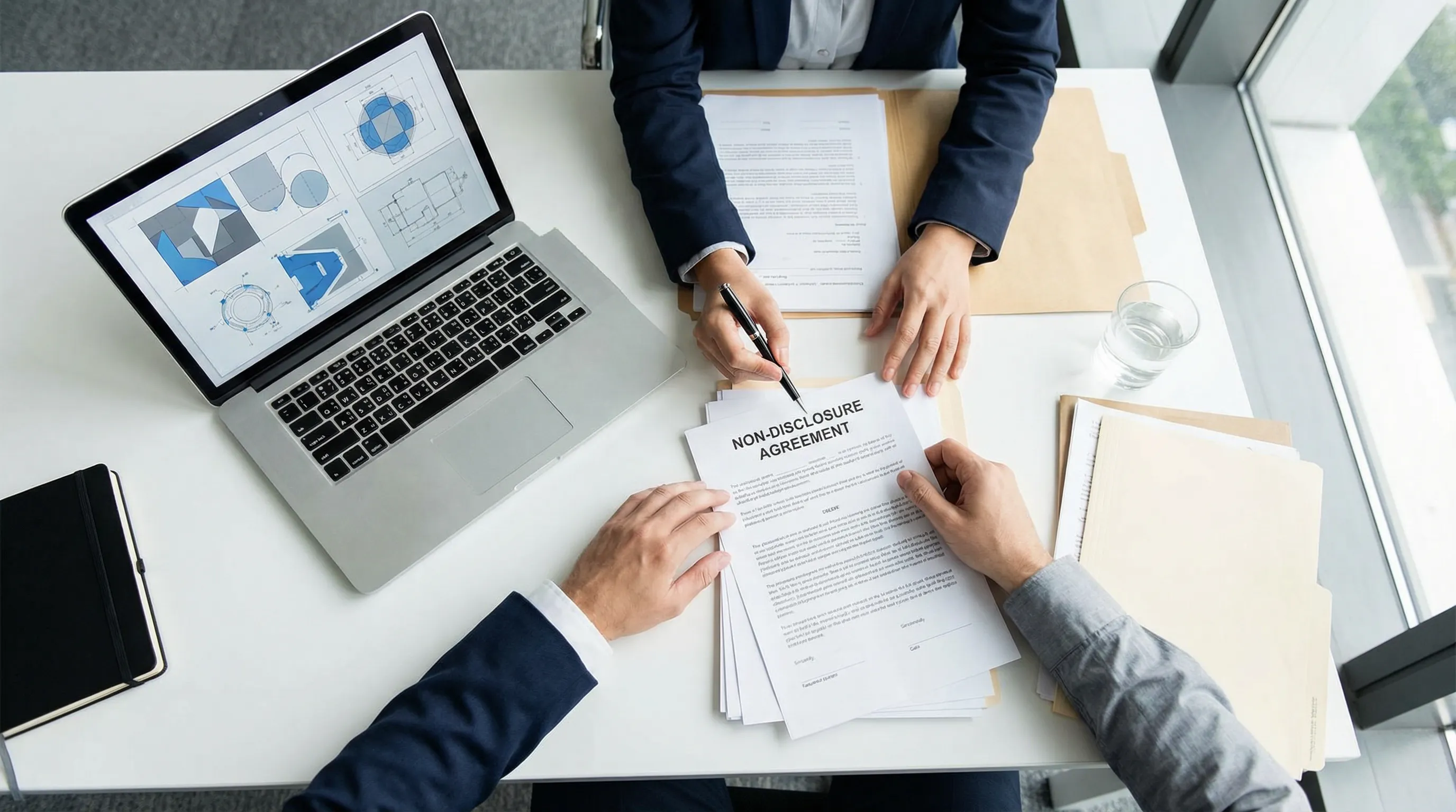 Buyer and supplier signing an NDA agreement with design files visible on laptop before sharing custom product specifications Buyer and supplier signing an NDA agreement with design files visible on laptop before sharing custom product specifications