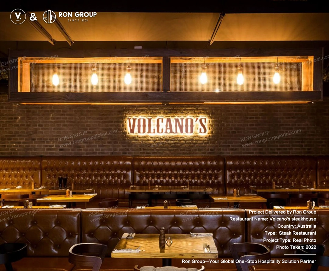 Wall branding and banquette seating at Volcano's Steakhouse Long custom tufted leather banquette seating beneath Volcano's illuminated wall signage