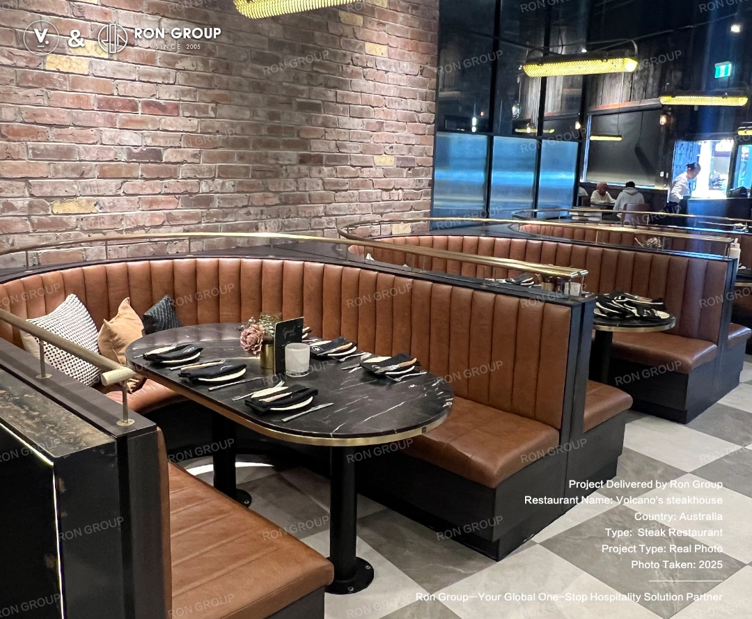 Curved booth seating at Volcano's Steakhouse Custom curved booth seating with dark marble-look tables and leather upholstery at Volcano's Steakhouse