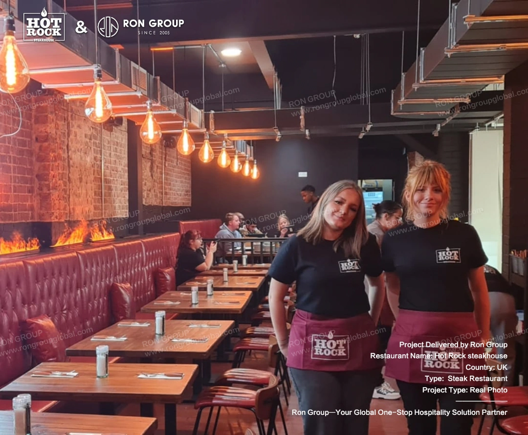 Hot Rock Steakhouse Staff and Dining Area Hot Rock Steakhouse staff standing inside the completed dining area with red leather booths, wooden tables, fire features, and pendant lighting.