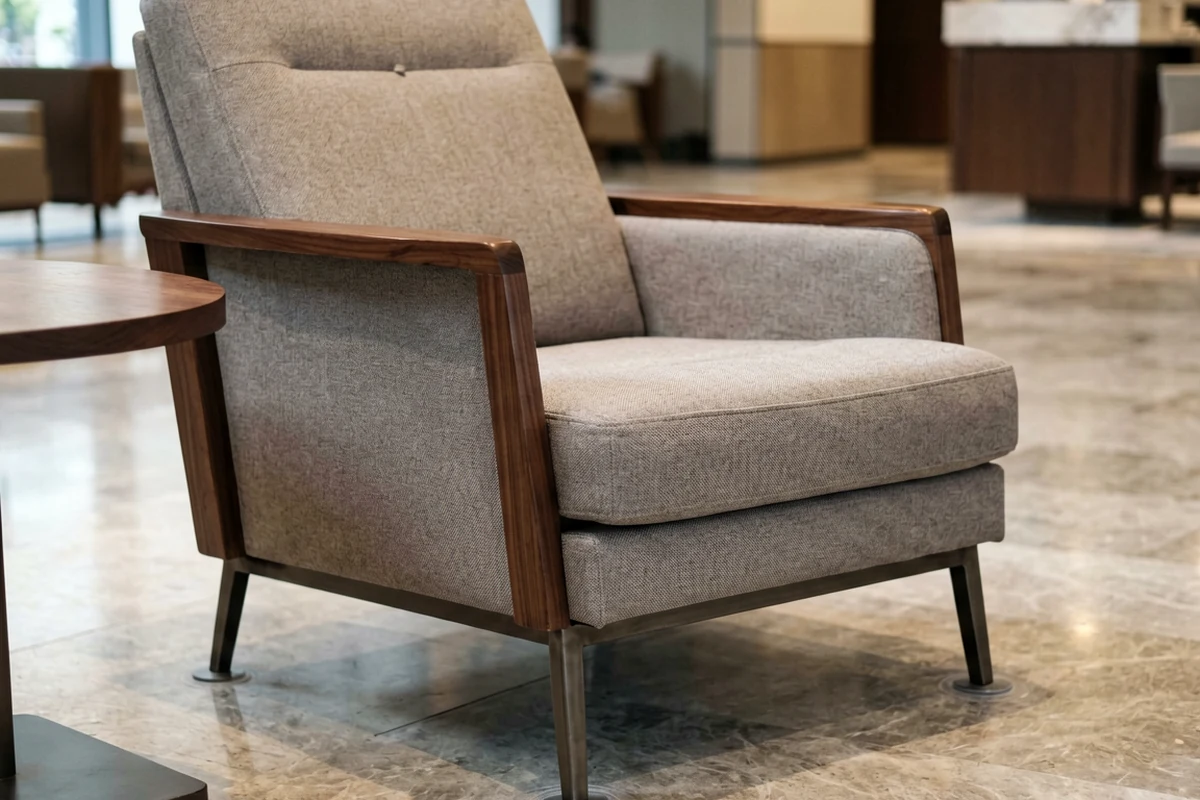Modern upholstered lounge chair with wooden armrests and metal legs in a hotel lobby setting